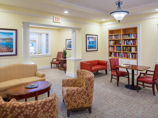 Atria Draper Place common area with seating and a bookcase full of books.