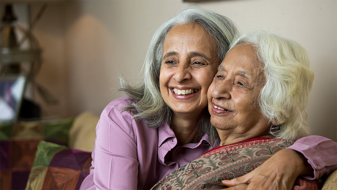 Senior resident and adult daughter hugging.