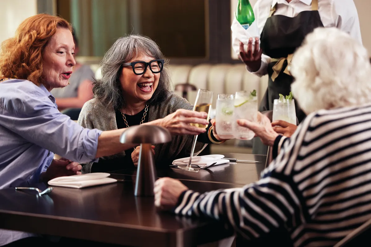 A group of friends clicks their glasses together. Cheers!