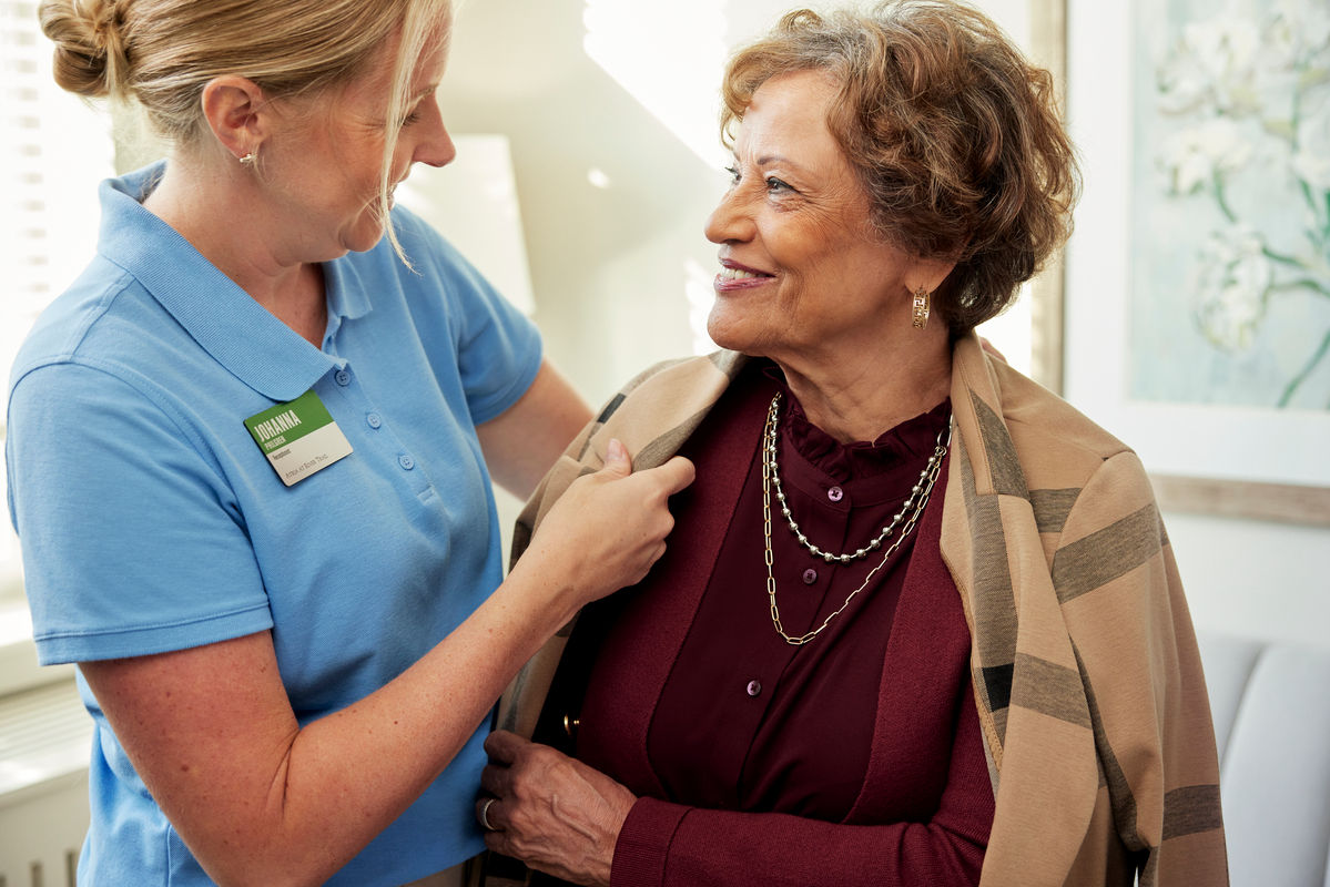 Caregiver helps older adult woman with an activity of daily living