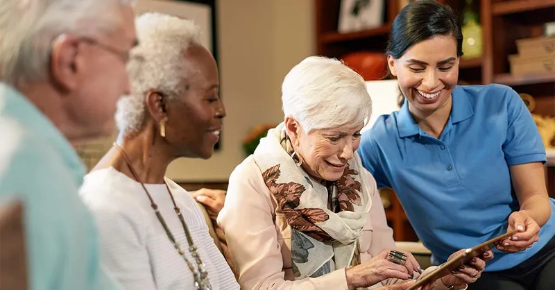 Three Atria Senior Living residents and an Atria employee looking at an iPad together
