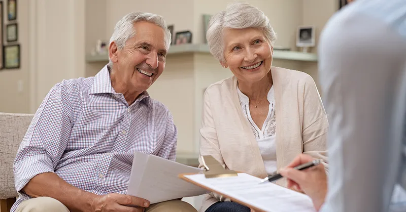 Happy elderly man and woman listening to various investment plans for their retirement.