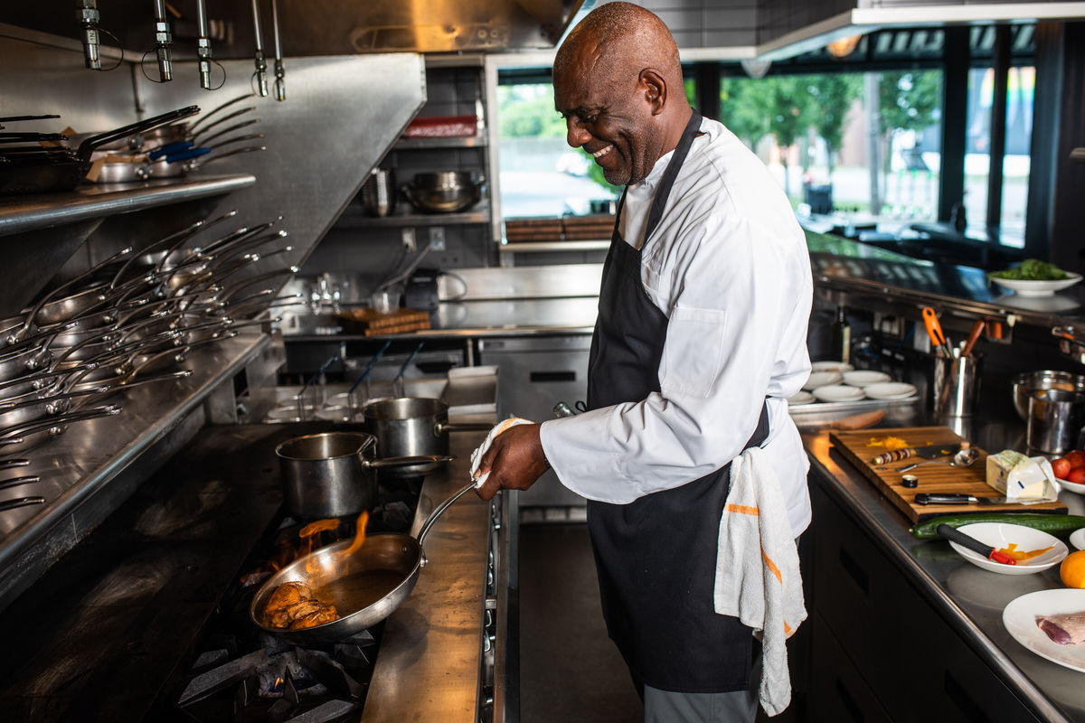 Coterie chef smiling as he prepares meal for residents