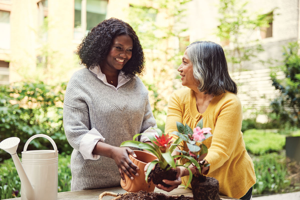 two women planting flowers together outside