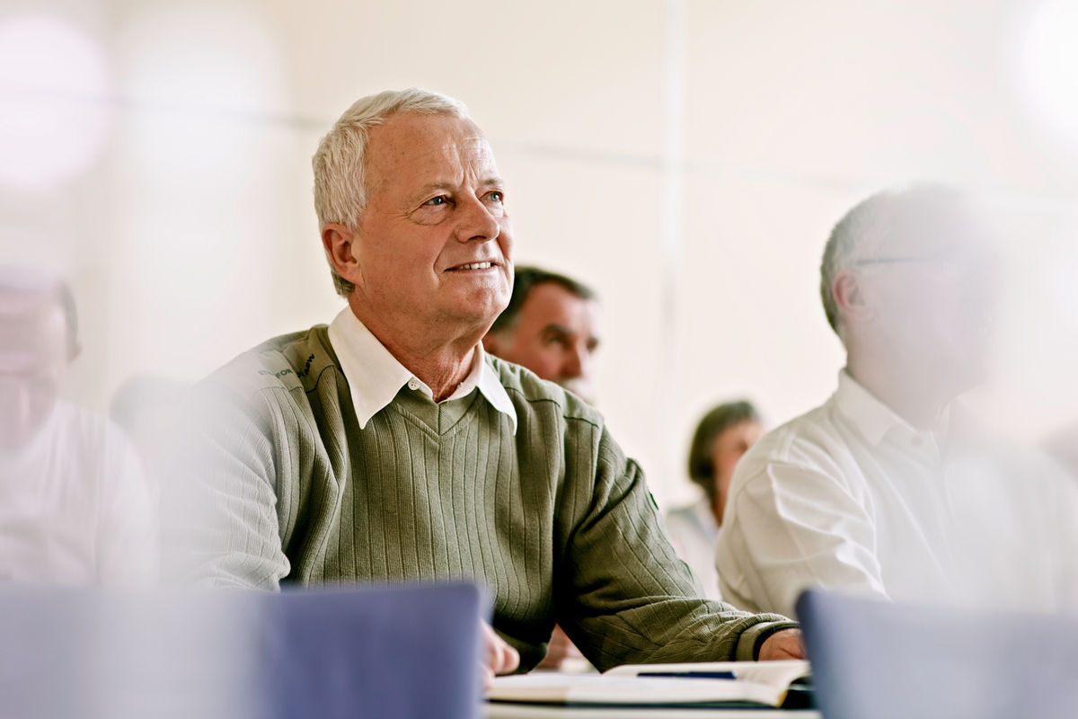 Senior man sitting at a table with an open notebook