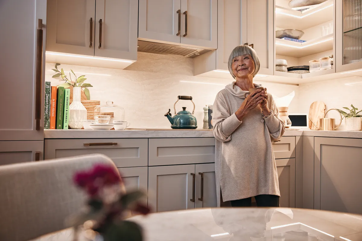 Woman stands in kitchen, holding a mug
