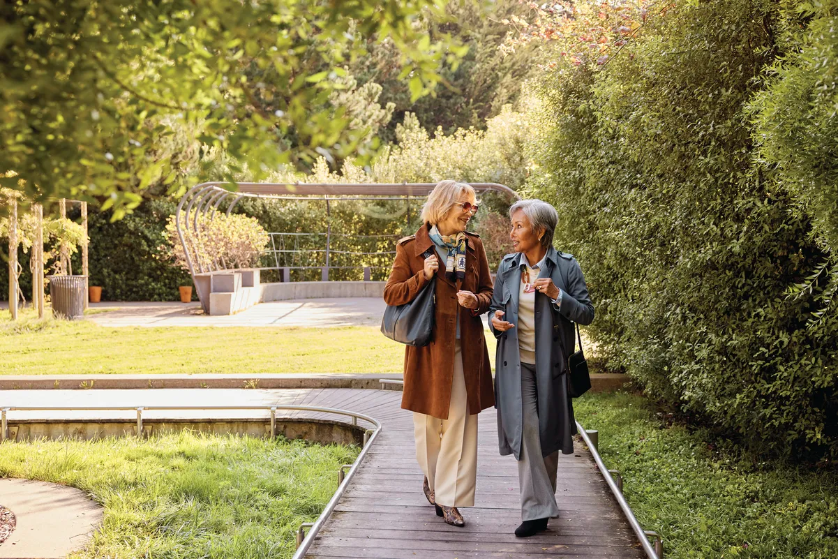 Two women enjoy walking through a park