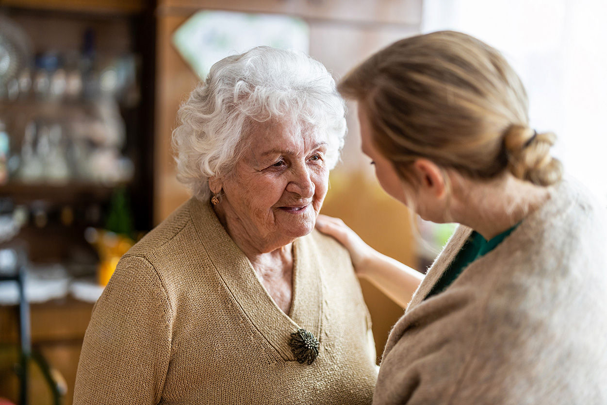 Senior resident standing with younger daughter who has her hand on the mother's shoulder.
