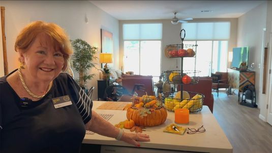 Senior resident in her apartment, with fall decorations on counter of her kitchen.