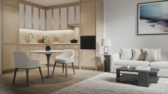 Modern open-plan kitchen and living room with light wood cabinets, a round dining table, gray chairs, a beige sofa, and abstract wall art.