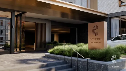 Entrance of a modern building with a sign reading "COTERIE 1001 Van Ness Ave," featuring glass doors and landscaped greenery.