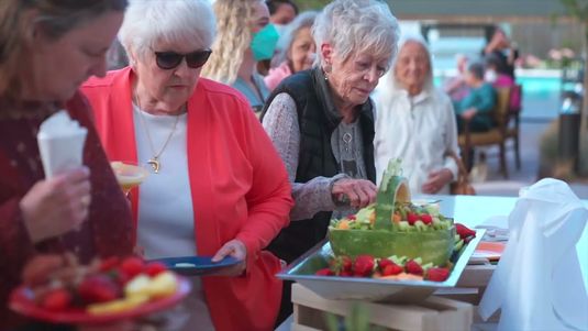 Older adults line up to try healthy fruits.