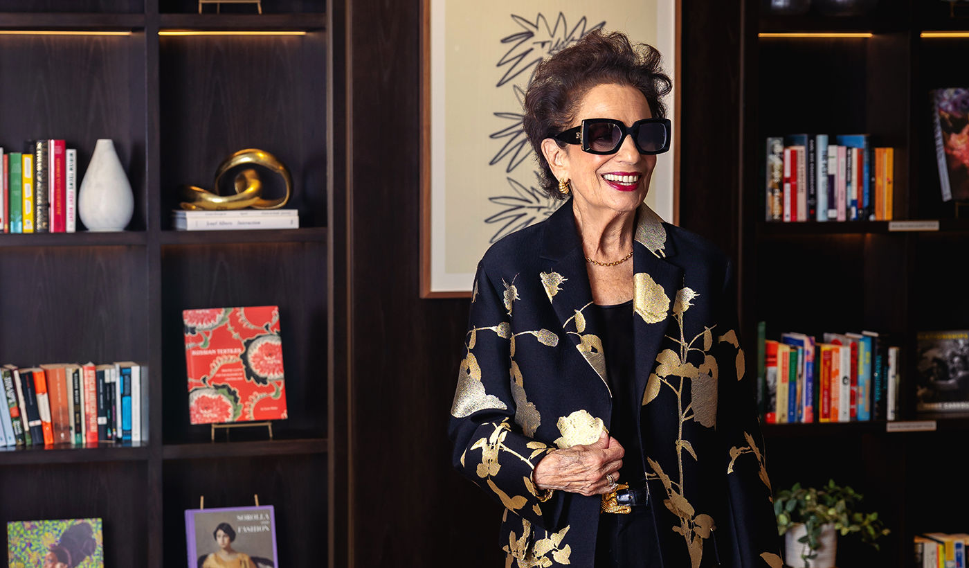 Coterie resident Marilyn standing in community common area dressed for a day out with sunglasses and a coat.