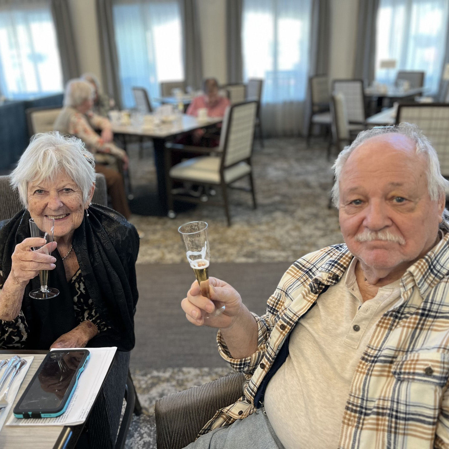 An older woman and man at a dining table with glasses to enjoy a toast at Holiday.