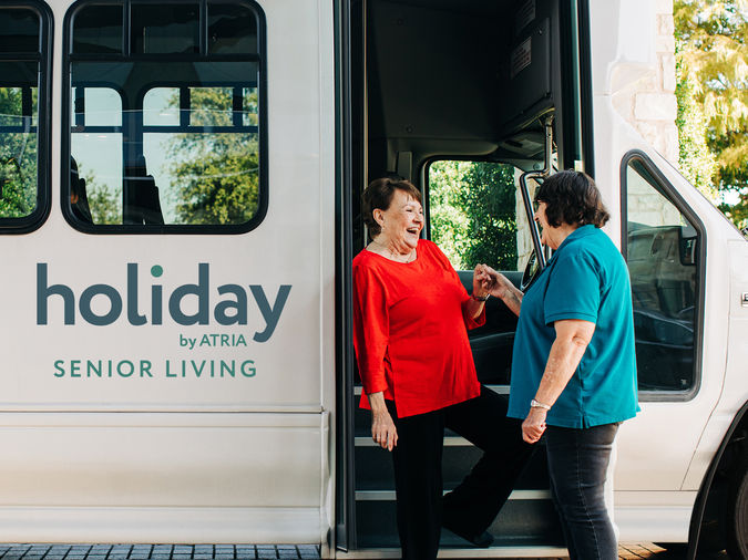 Holiday staff assisting resident out of the community bus
