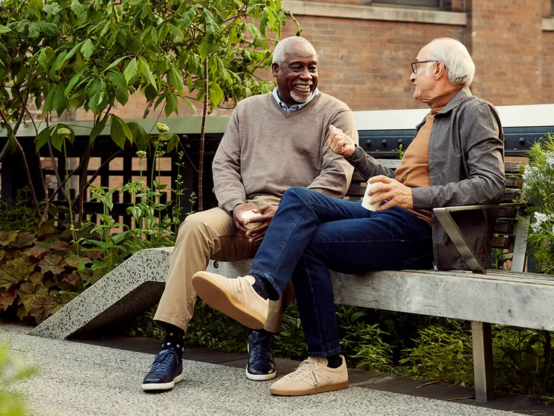 two senior men chatting on an outdoor bench