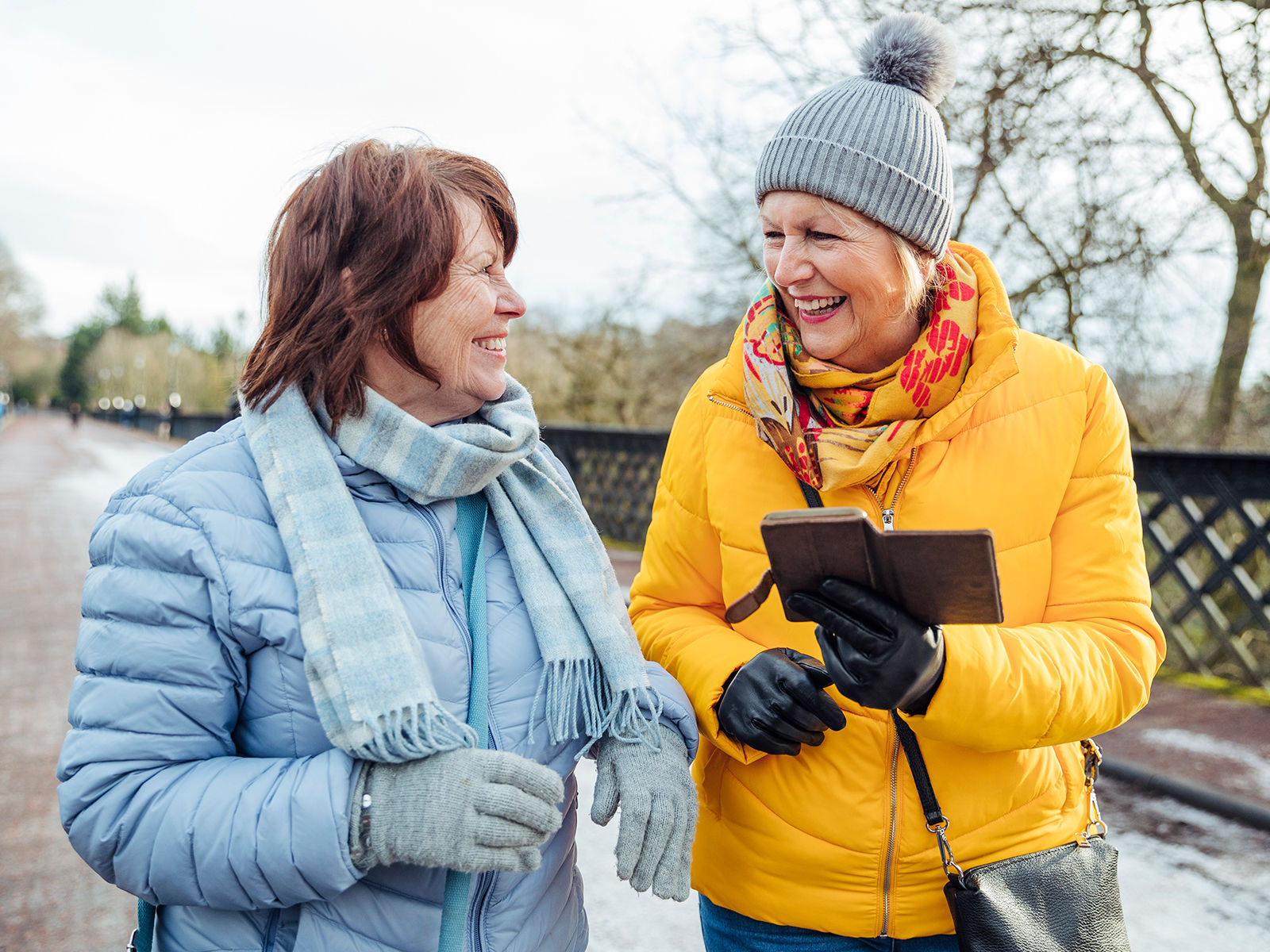 two senior woman walking together in the park on a winter day