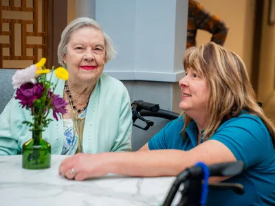atria staff kneeling down at a table to chat with residents