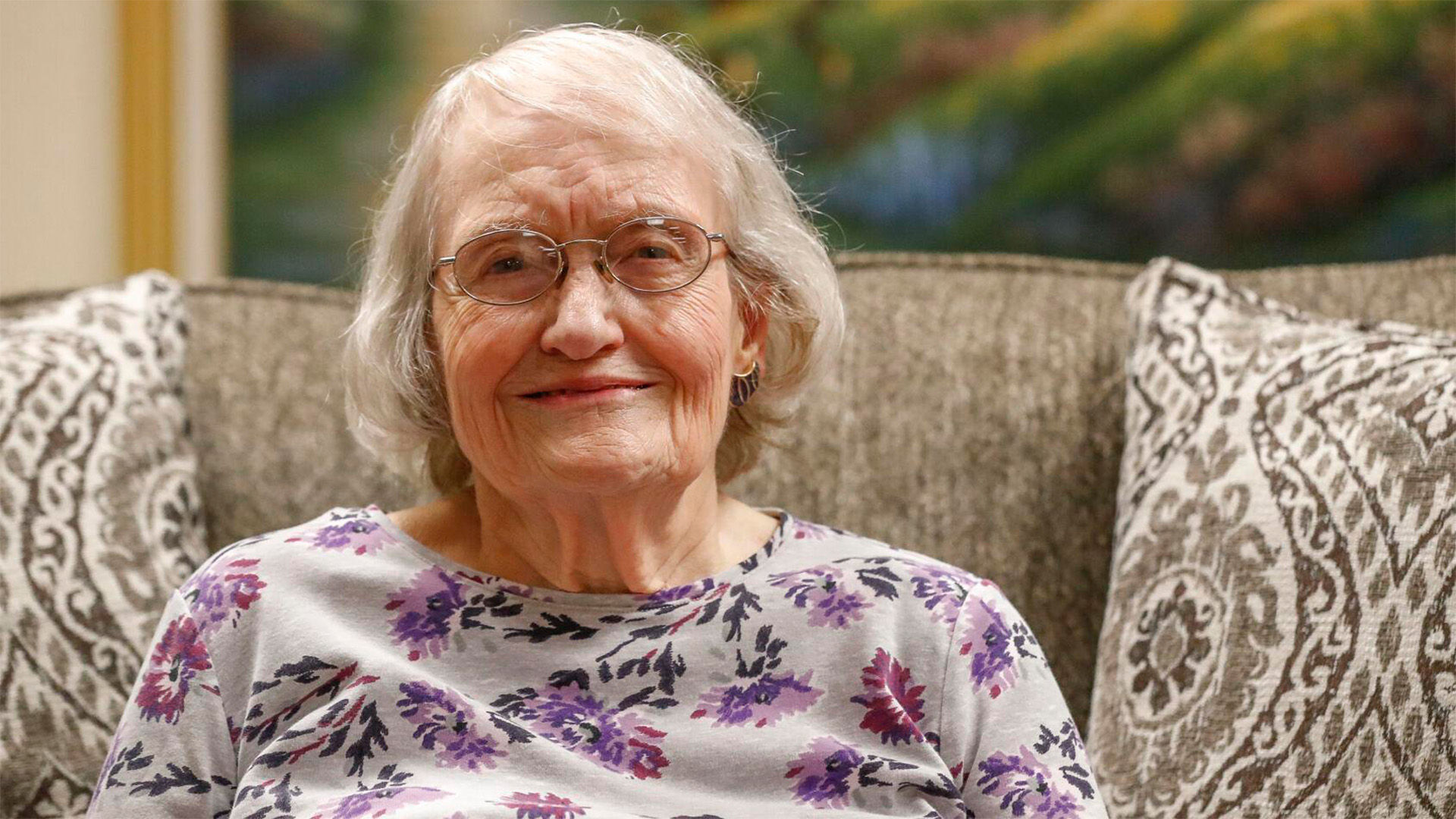 Photo of Holiday resident Janice Halverson, she is smiling and sitting on a couch.