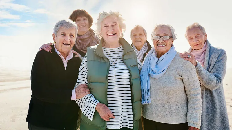 Seven older women standing together on the beach