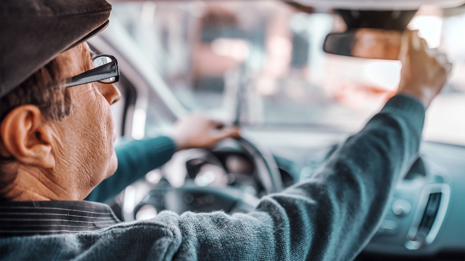 Senior man adjusting mirror in car