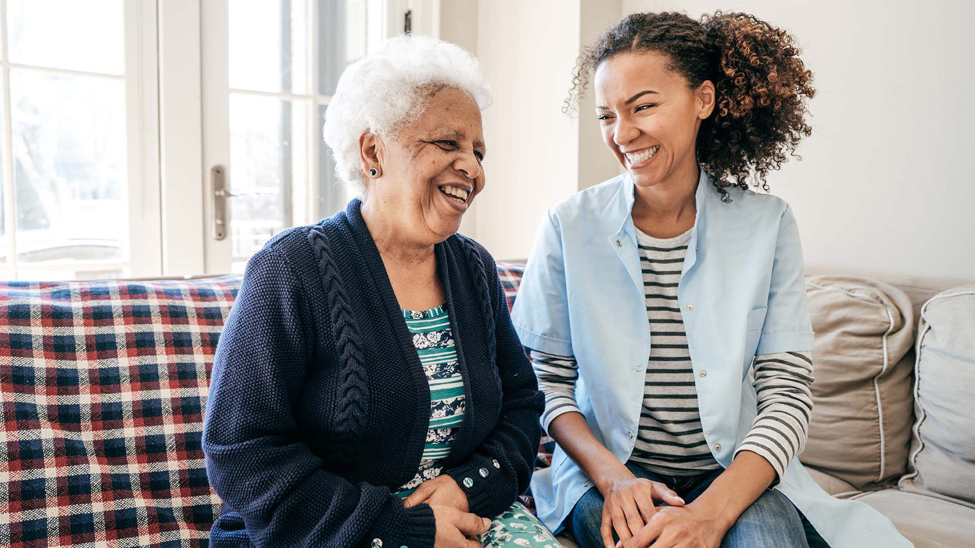 Older woman and daughter sitting on the couch and laughing together