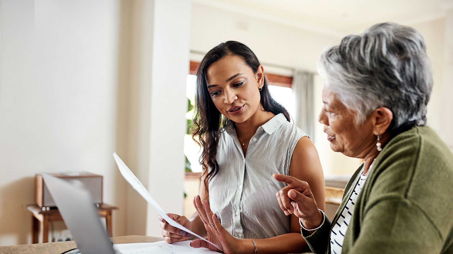 Cropped shot of an attractive young woman sitting and explaining financial documents to her grandmother in their home