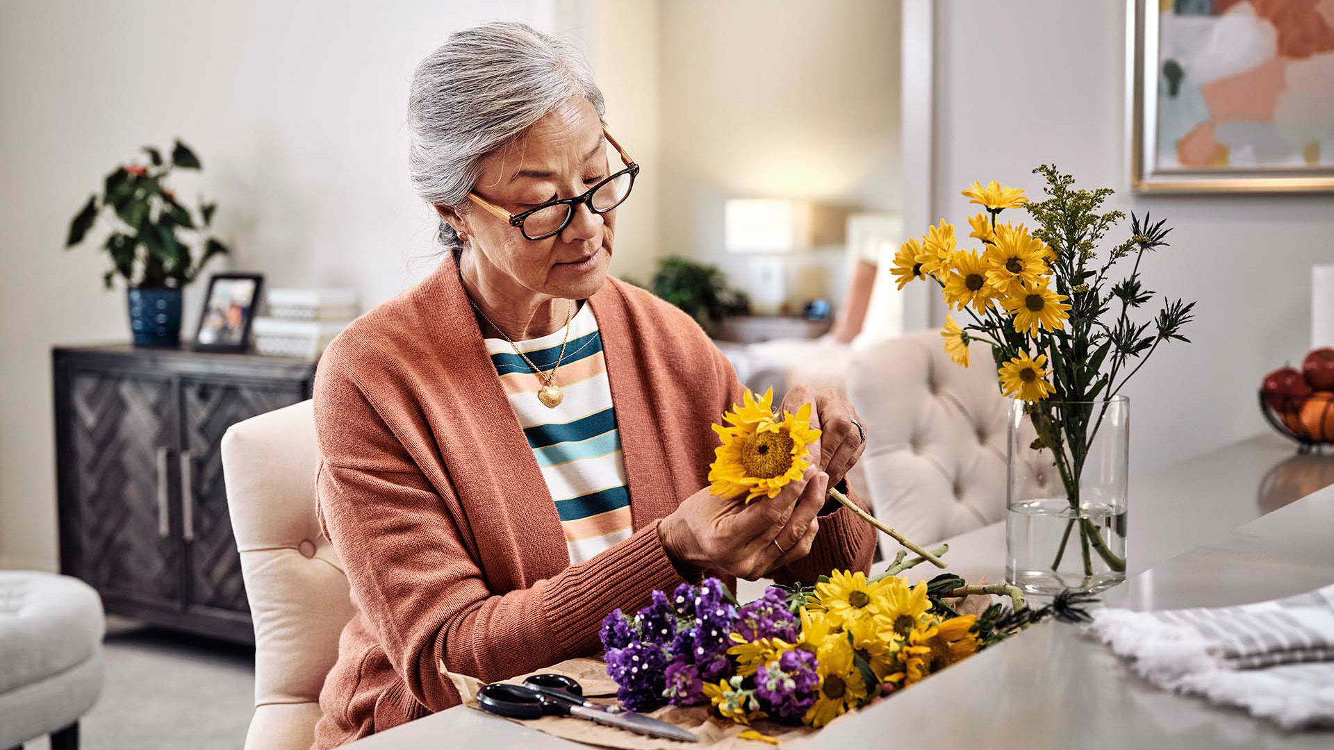 Older female putting together a vase of flowers