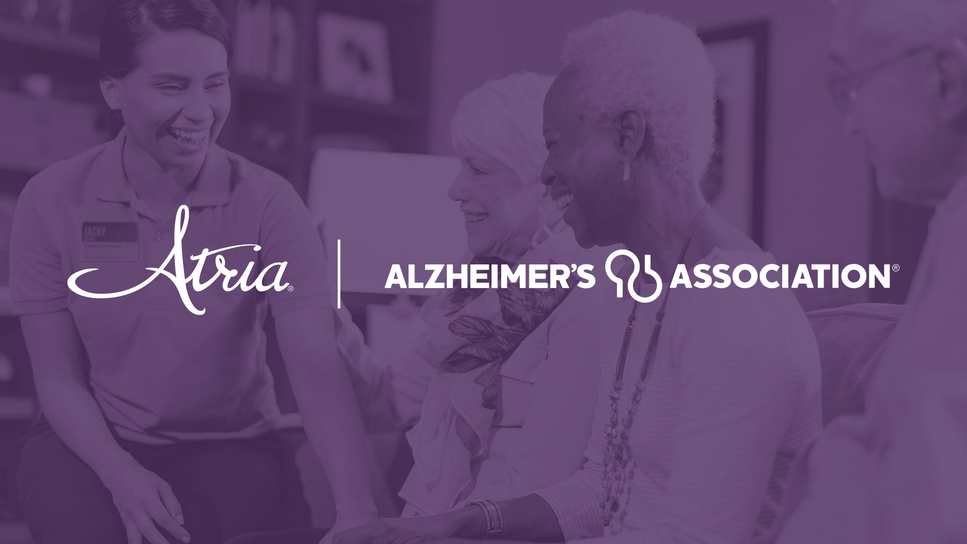 Atria and Alzheimer's Association logos on a purple overlay on top of a background of seniors interacting with an Atria employee