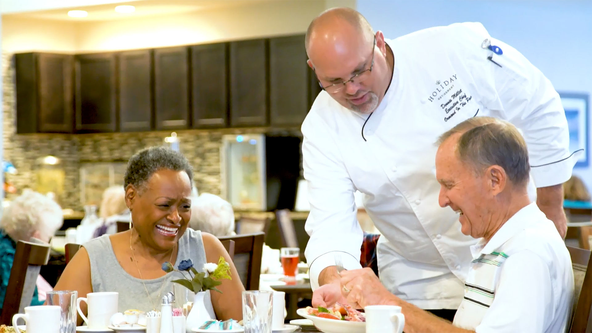 Holiday chef serving salad to resident in dining room.