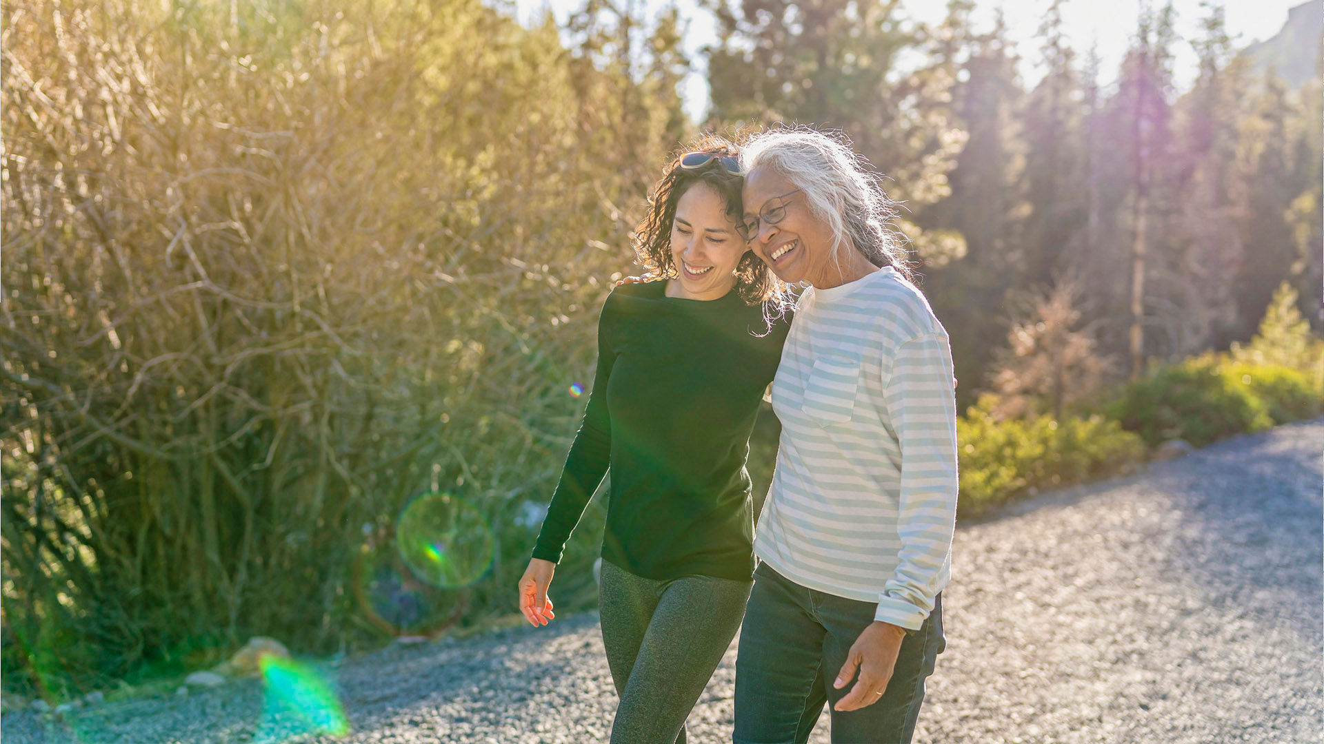 A beautiful mixed race young adult woman embraces her vibrant retirement age mother