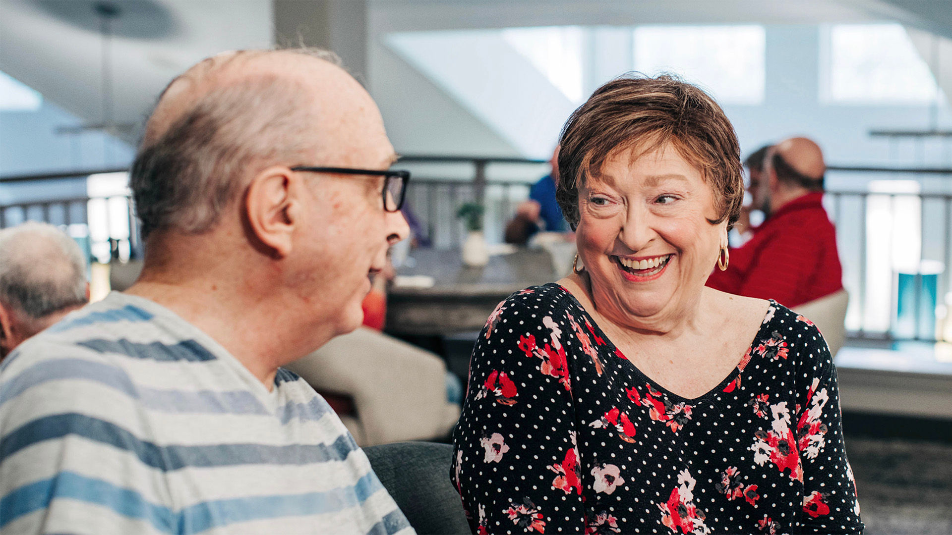 Senior man and woman smiling at eachother in the activity room at a Holiday community.