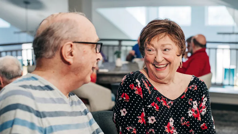 Senior man and woman smiling at eachother in the activity room at a Holiday community.