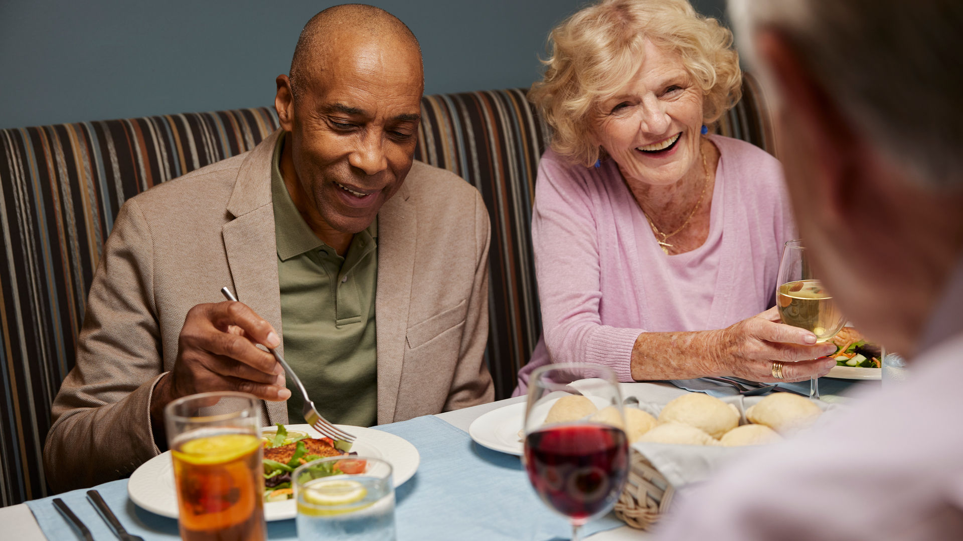 bi-racial senior couple enjoying a meal with friends