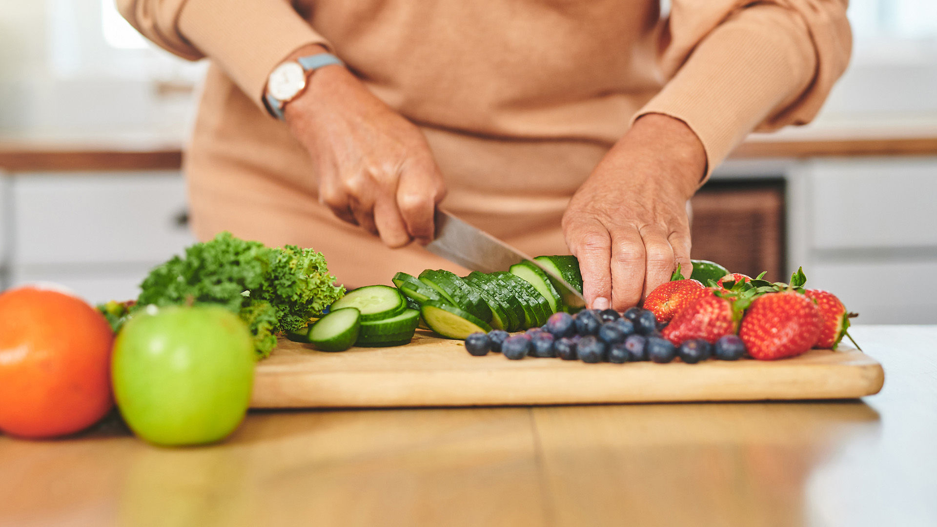 Senior chopping veggies on wood cutting board