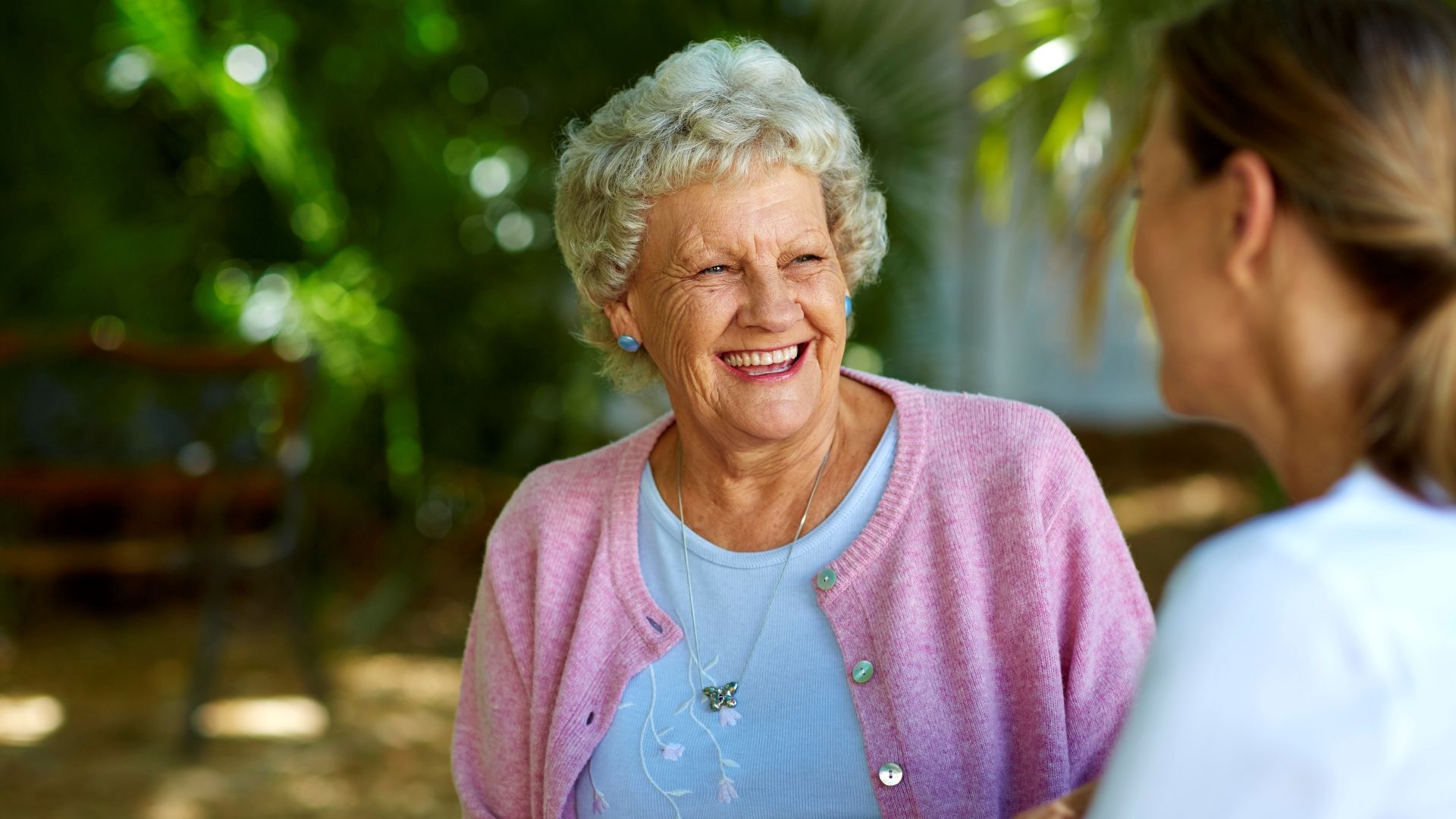 Smiling senior woman sitting with a community staff member laughing.