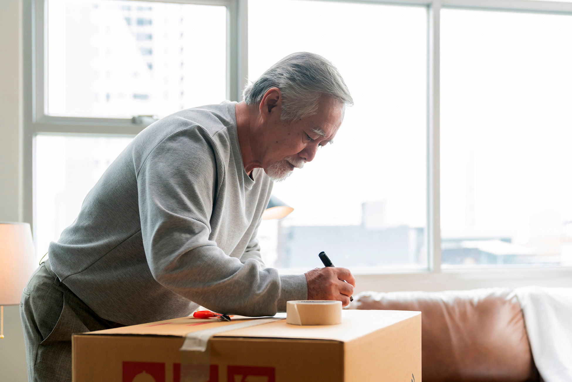 Senior man packing and labeling a moving box
