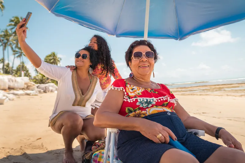 Family enjoying the weekend on the beach by taking a selfie and sitting under an umbrella