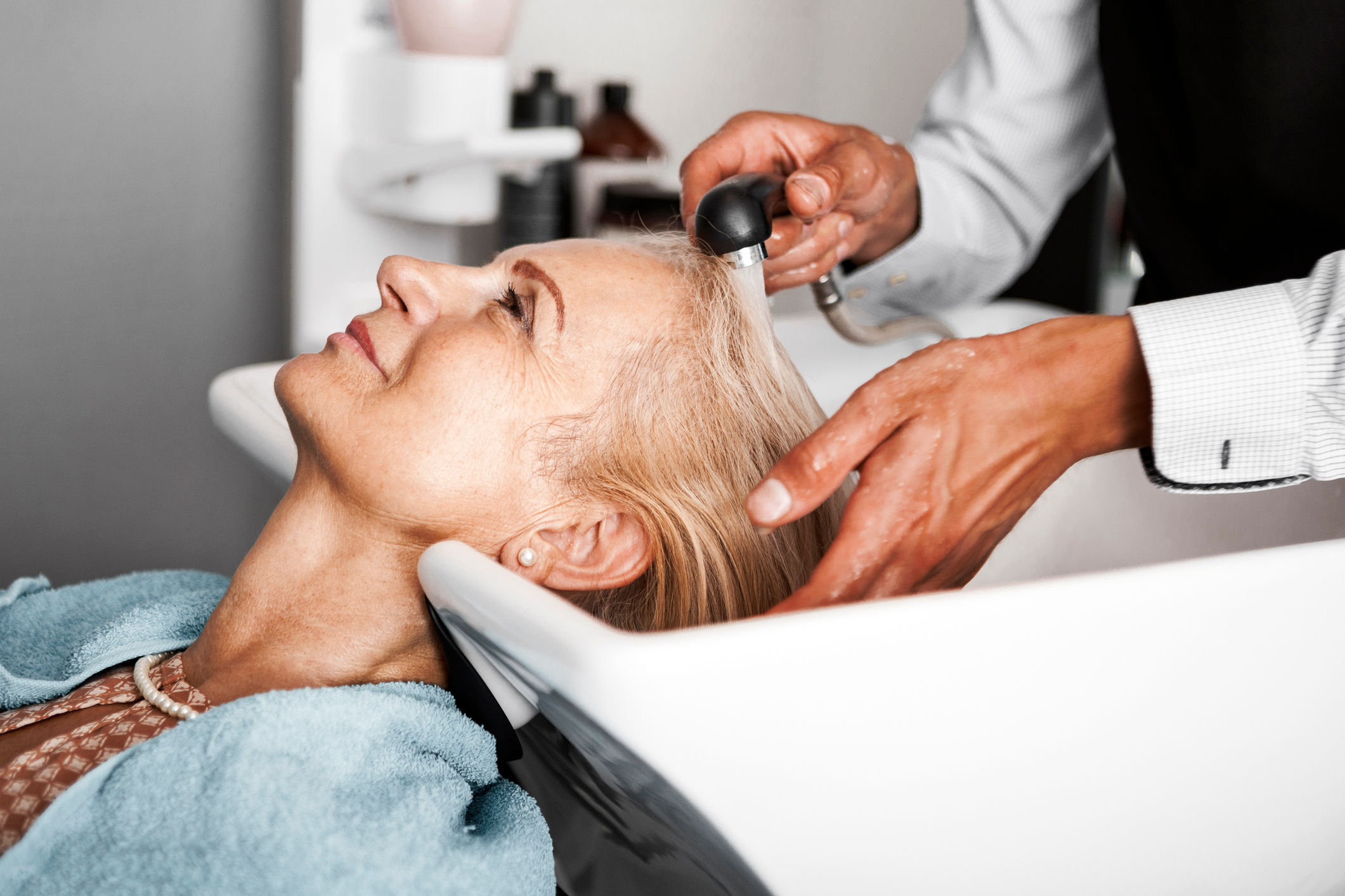 Senior woman having hair washed at salon