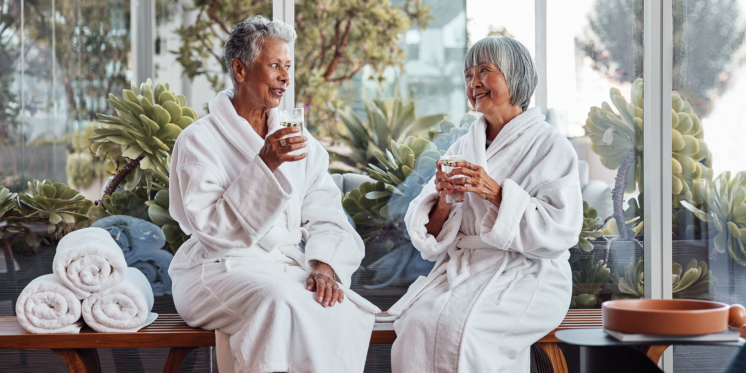 Two senior residents having water in the community spa lounge
