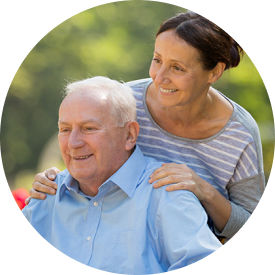 Senior woman pushes senior man in wheelchair