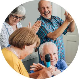 Senior residents singing karaokee, clapping and smiling.