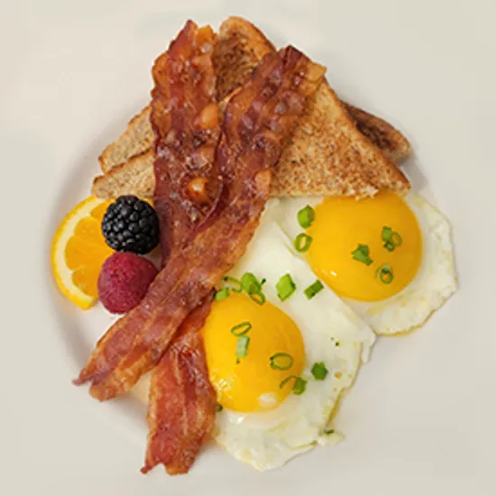 Two eggs sunny side up with bacon and toast