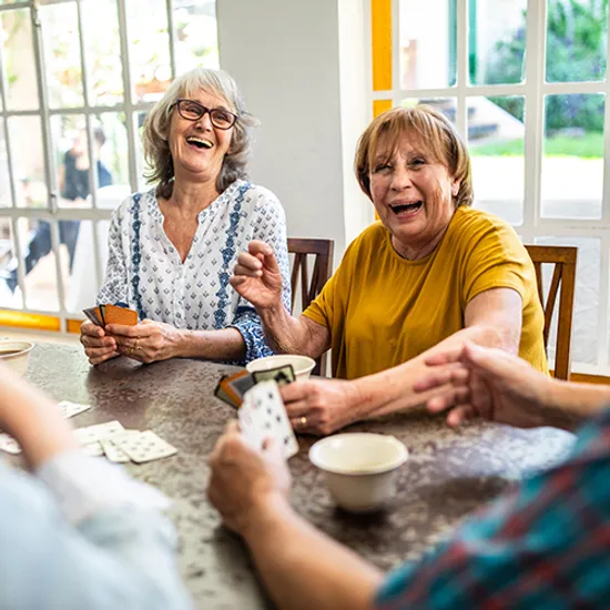 Group of Senior friends playing cards, sitting at dining room and having good time