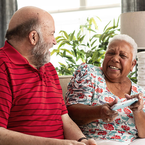 senior man and woman laughing on the couch together