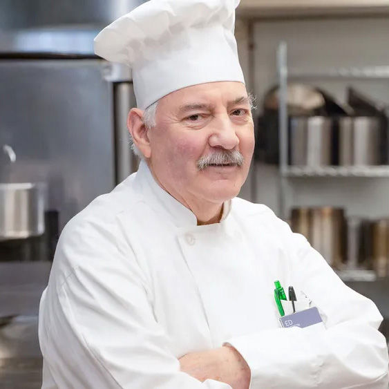 Chef Edward in the kitchen with his arms crossed and smiling