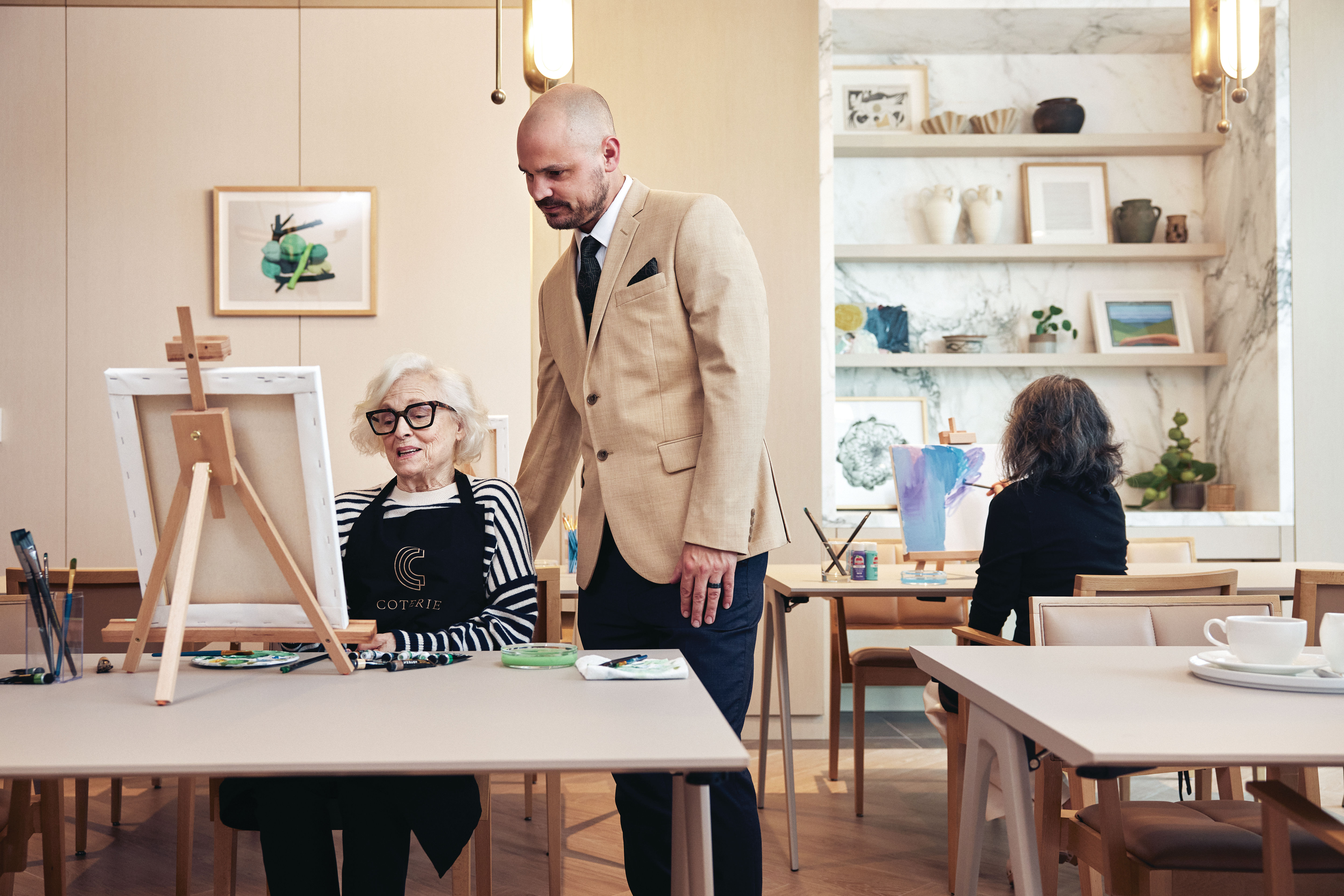 A Coterie resident and a staff member looking at an easel on the table in the Club Room