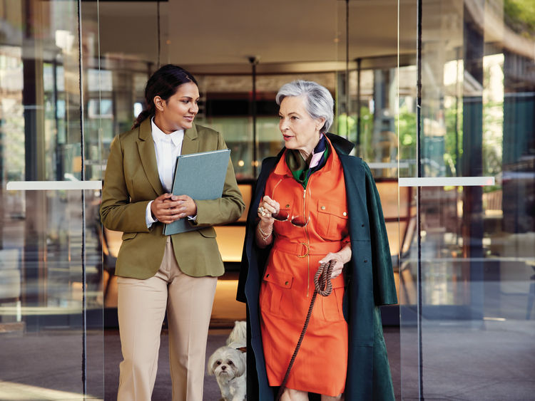 senior woman walking her dog through building entrance alongside staff member