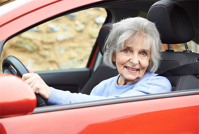 Portrait Of Smiling Senior Woman Driving Car