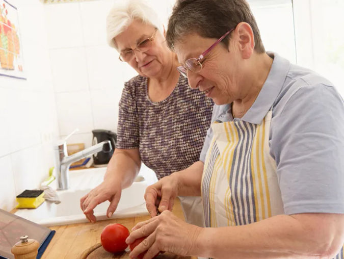 two senior women preparing a meal together